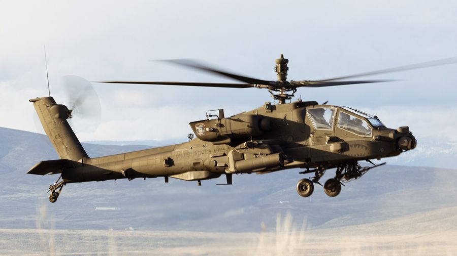 An AH-64 Apache attack helicopter flying low