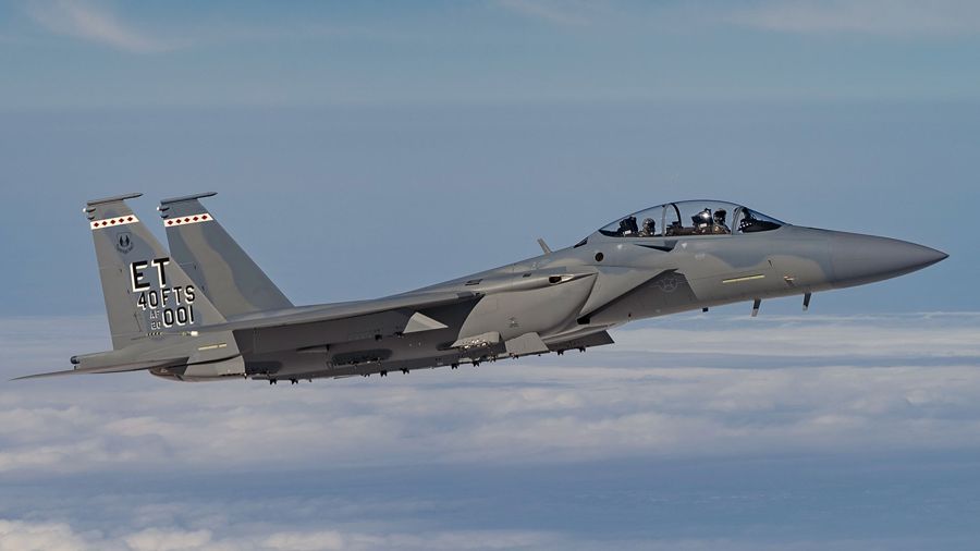 An F-15EX fighter in flight above clouds