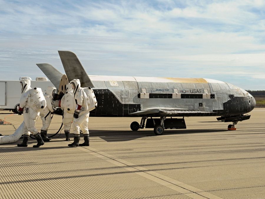 The X-37B spaceplane on a runway attended by crew in protective suits